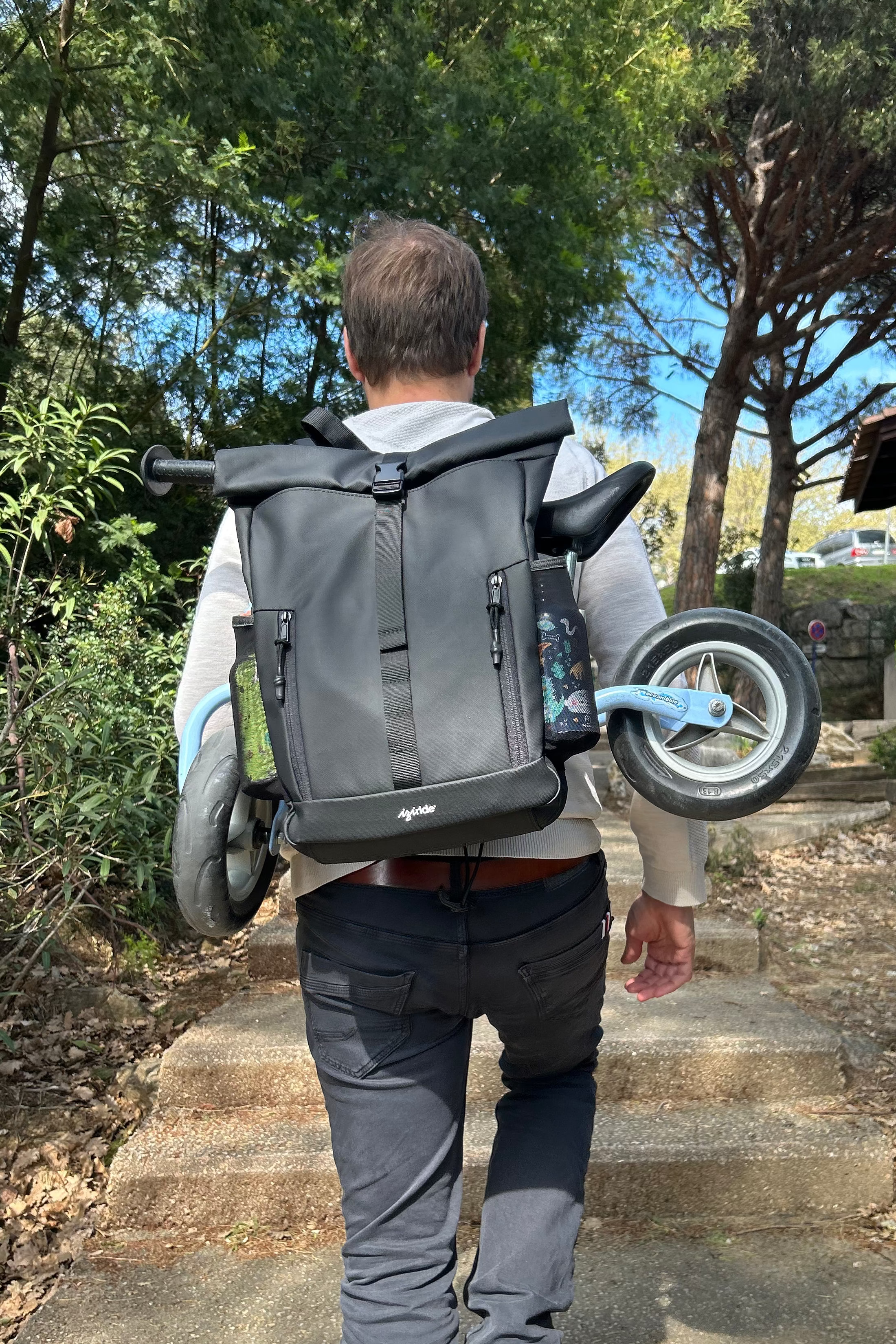Adulto que lleva a la espalda una bici de equilibrio infantil con la mochila Iziride